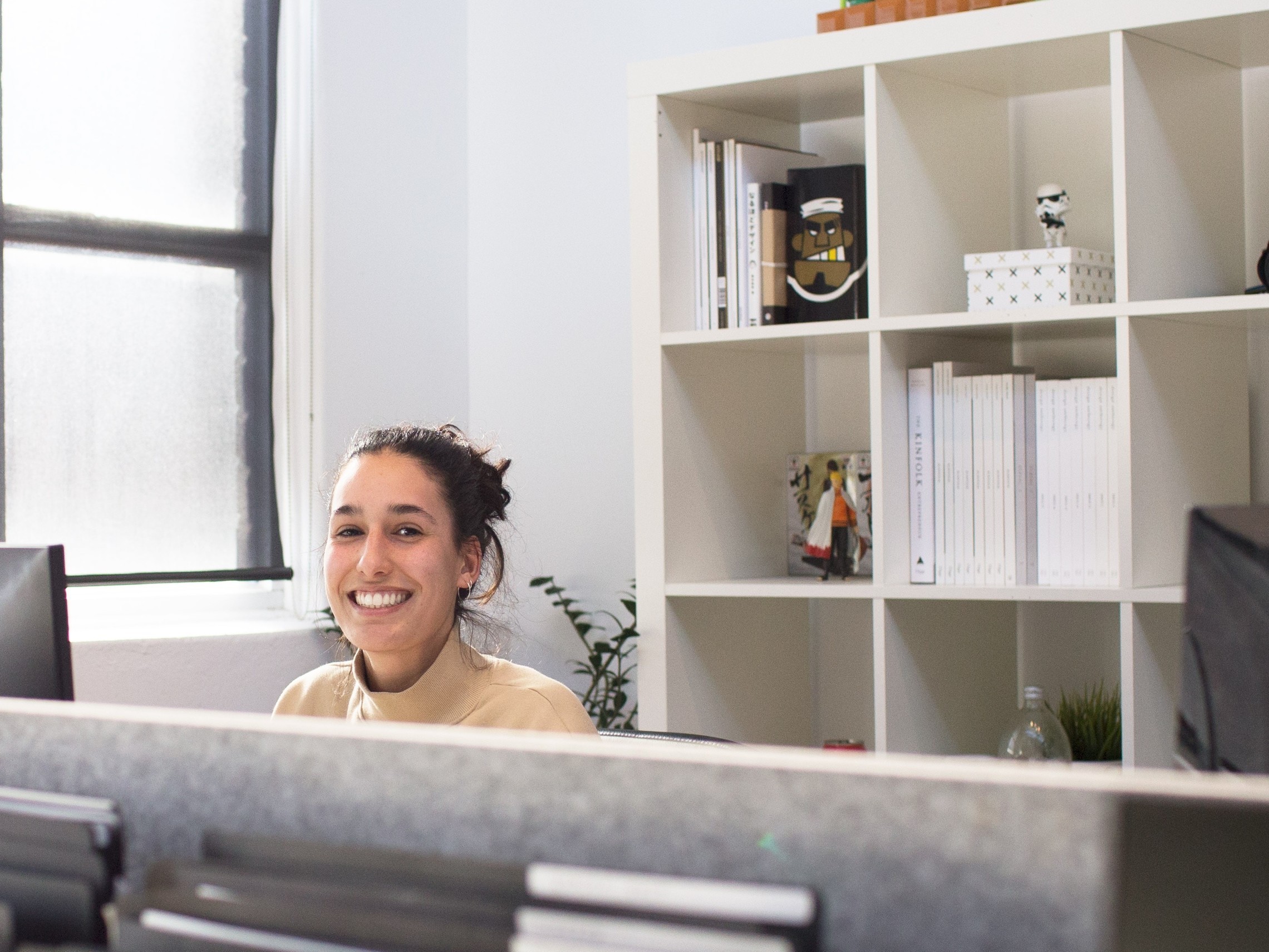 young woman smiles while sitting behind her desk